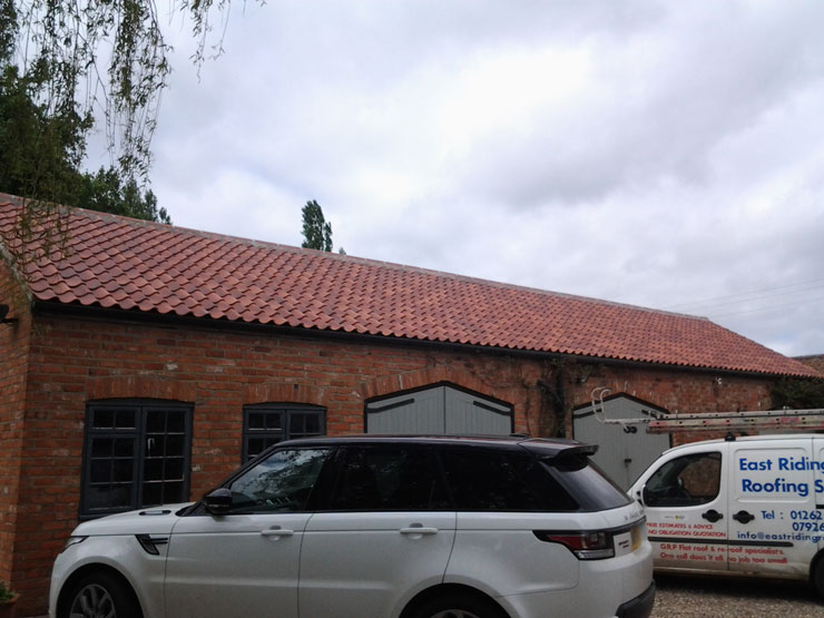 Vehicles parked in front of a re-roofed outbuilding